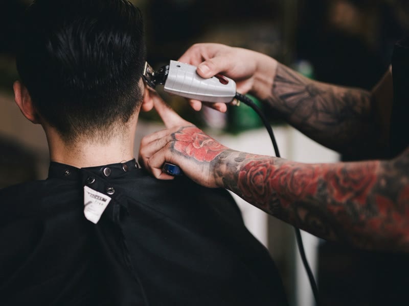 Barbier werkt met een tondeuse in iemands nek
